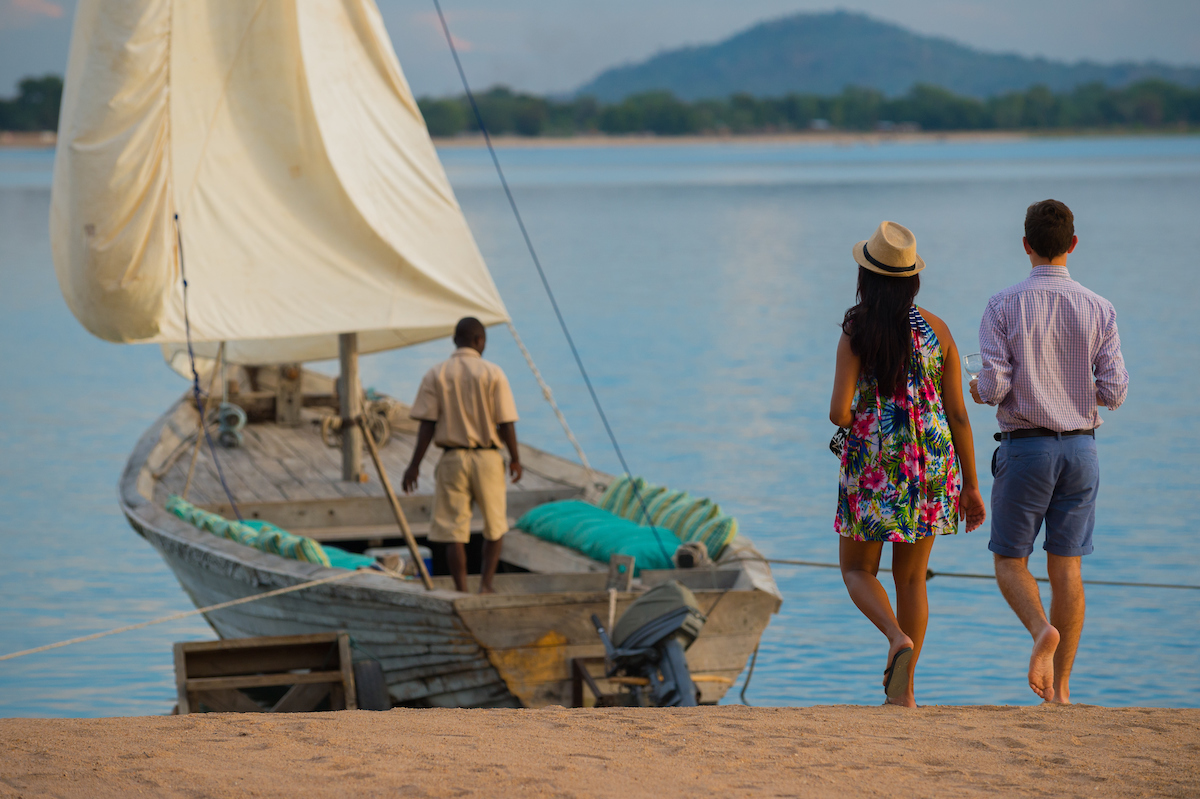 A couple beside a traditional boat on Lake Malawi